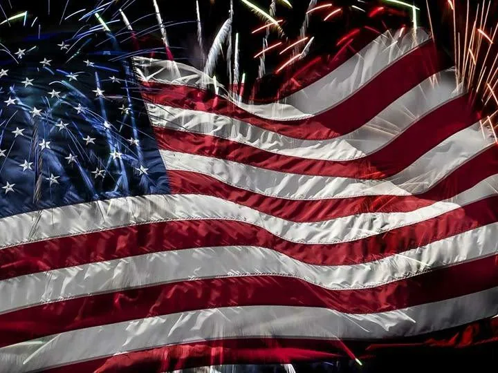 American flag waving with fireworks behind it